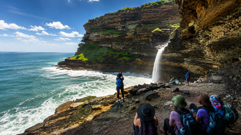 Wild Coast waterfall cascading into the Indian Ocean as hikers explore South Africa's dramatic coastal cliffs on a WildForge Adventures journey.